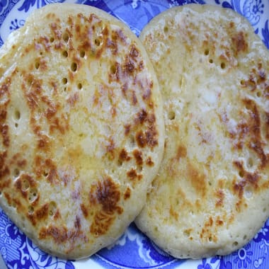 Easy Homemade Pikelets spread with butter on a blue patterned plate